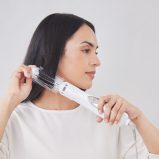 A woman with long, smooth dark hair using Panasonic hair styler with roller brush