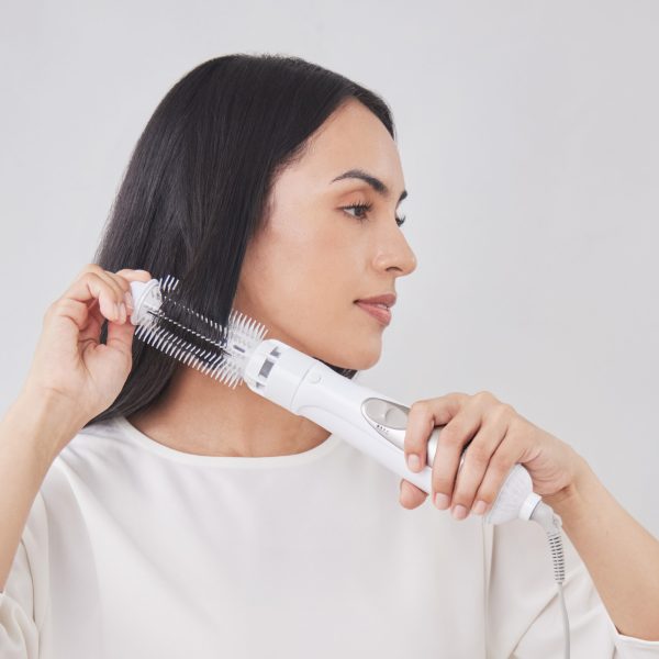 A woman with long, smooth dark hair using Panasonic hair styler with roller brush